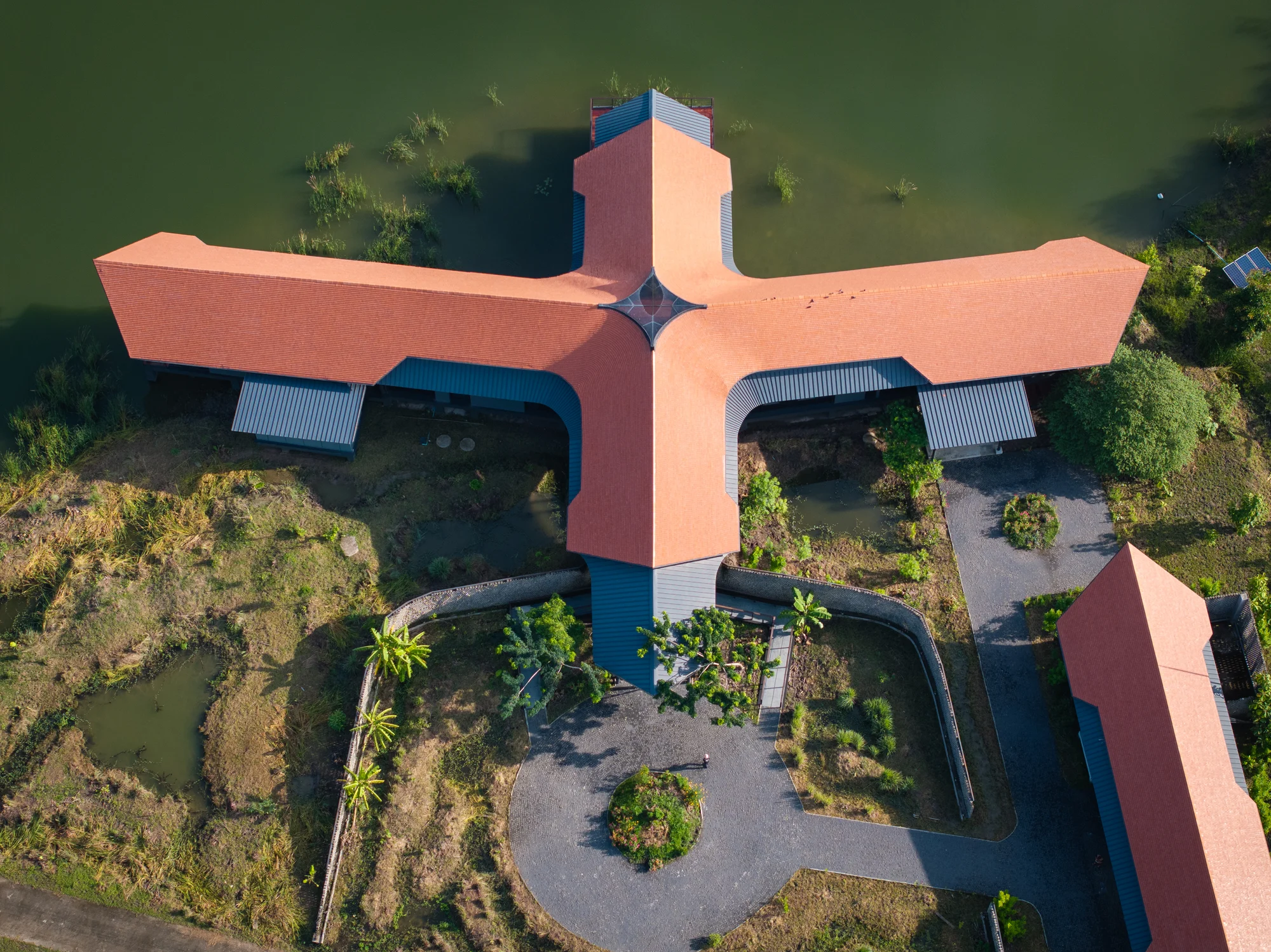 Aerial view of the intersecting roofs of Nongchok House beside the lake